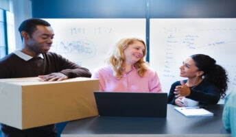 Man holding box, talking to colleagues. Source: Tech.co