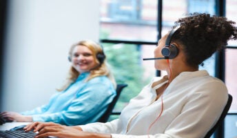 Two talking colleagues wearing headsets. Source: Tech.co