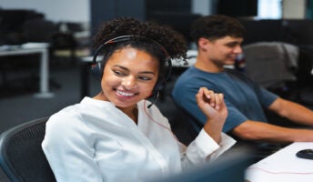 Two smiling colleagues on headsets. Source: Tech.co