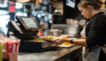 Woman taking a payment at a cash register in a restaurant