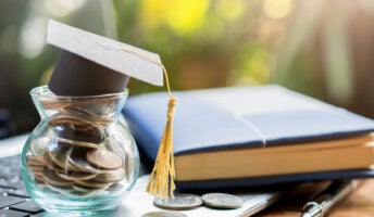 College student graduation gap on top of saving pot on laptop illustrating saving to pay student loan debt