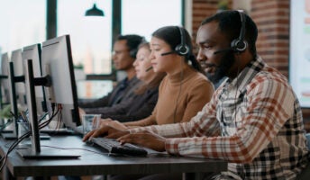 Four employees sat at desks with headsets on.