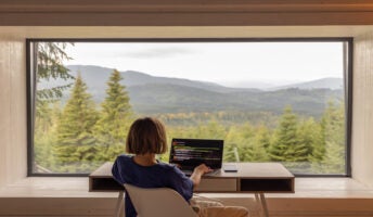 Woman working from home in front of a beautiful forest view