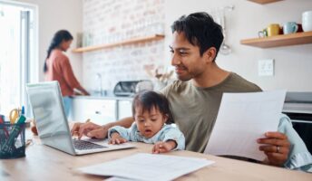 Father using laptop with child on his lap