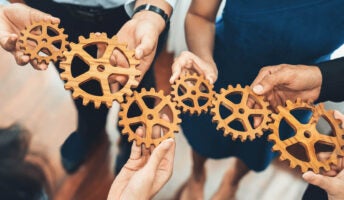 Office worker holding cog wheel as unity and teamwork in corporate workplace concept