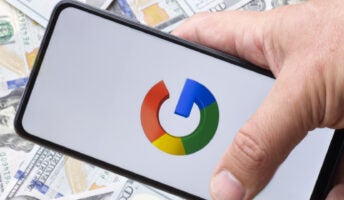 Google logo on a smartphone silhouette hold in hand. One hundreds dollar bills on the blurred background