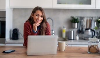 Businesswoman with hand on chin while having video call on laptop computer in home.