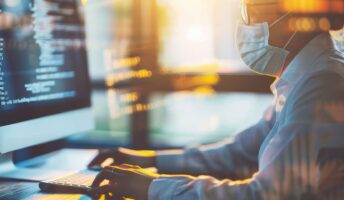 A woman wearing a COVID mask at the computer.