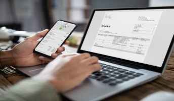 Businessman's Hands Working On Invoice On Laptop