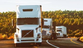 three trucks driving down a highway