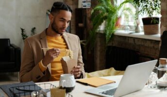 A remote worker eating in front of a laptop