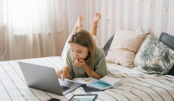 A remote worker on a laptop in her bed.