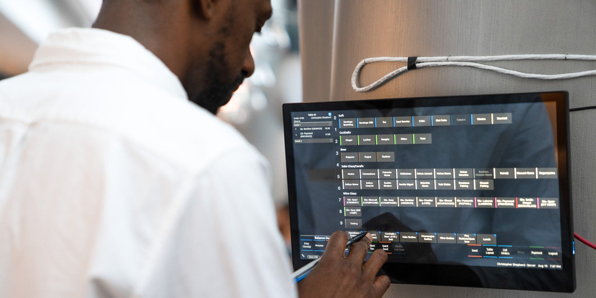 A restaurant worker uses SpotOn POS on a mounted display