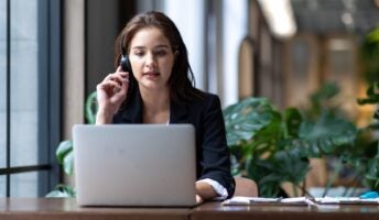 Woman enjoys some of the benefits of VoIP systems working on laptop