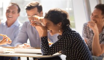 A woman laughs as her and her team get pizza.