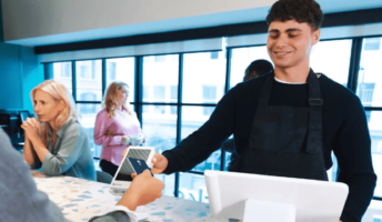 A person takes a payment at a cafe. Source: Tech.co